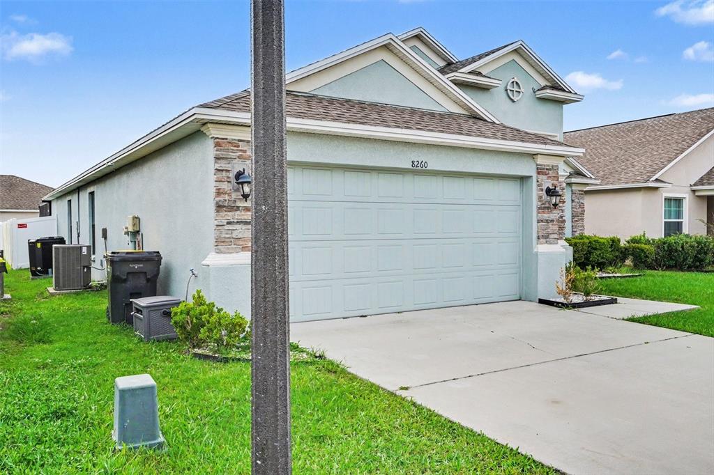 A light blue house with a two-car garage and stone accents on the front facade — 8260 CAMPBELL CROSSING WAY, LAKELAND, FL