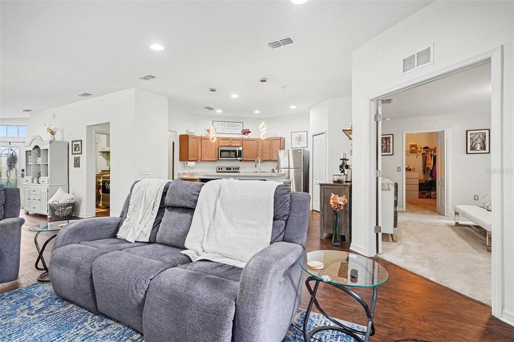 A living room with a gray sofa faces an open kitchen with wood cabinets — 8260 CAMPBELL CROSSING WAY, LAKELAND, FL