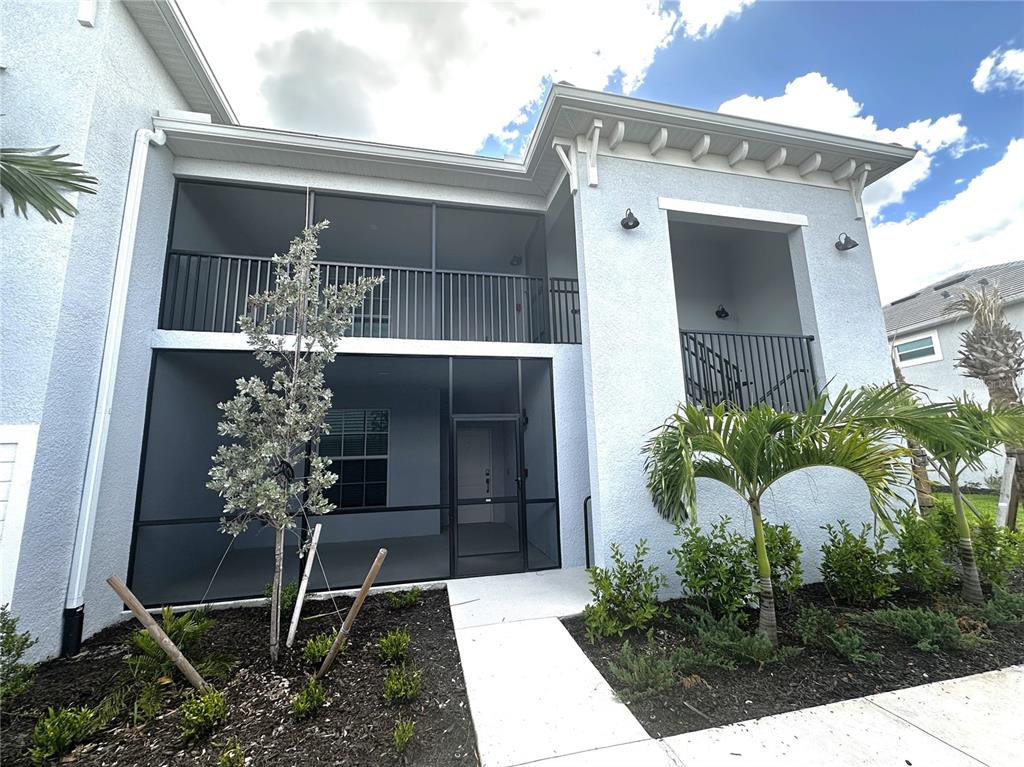 A two-story building exterior features a screened-in patio, a balcony, and a concrete walkway — 14231 HERITAGE LANDING BOULEVARD UNIT 1928, PUNTA GORDA, FL
