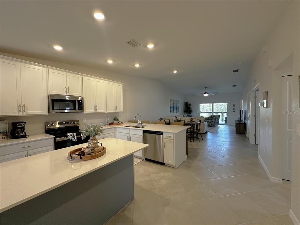 A modern kitchen with white cabinets and a large island opens into a living area — 14231 HERITAGE LANDING BOULEVARD UNIT 1928, PUNTA GORDA, FL