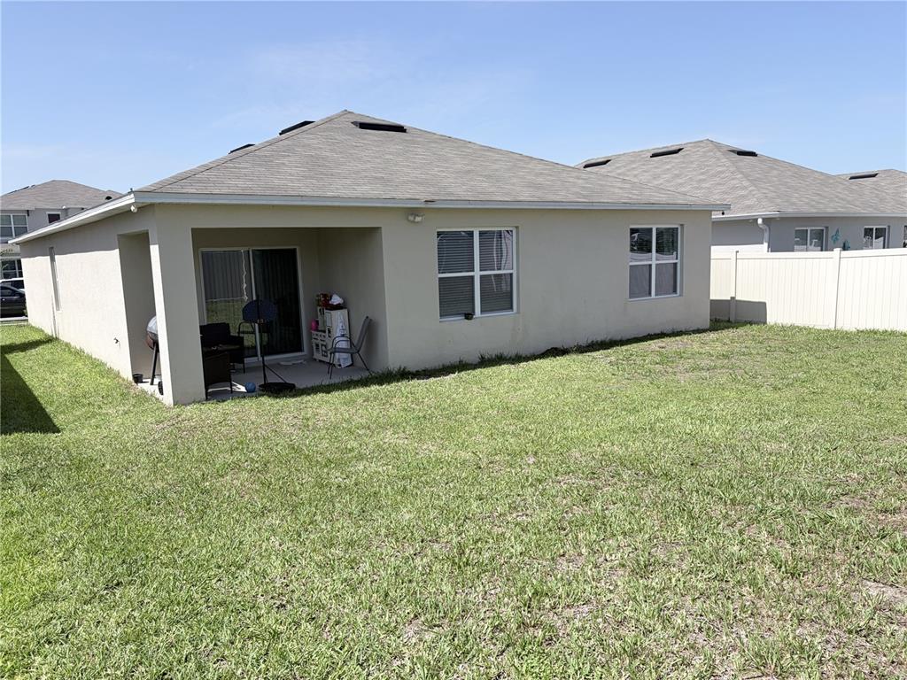 The exterior view shows the back of a beige house with a covered patio — 1270 IGUANA LOOP, DAVENPORT, FL