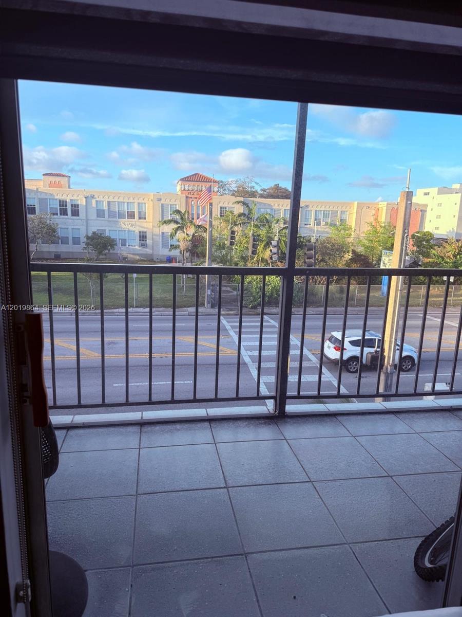 A balcony with tiled flooring overlooks a street, a crosswalk, and a large building — 1250 NE 125th St # 317A, North Miami FL 33161, NORTH MIAMI, FL