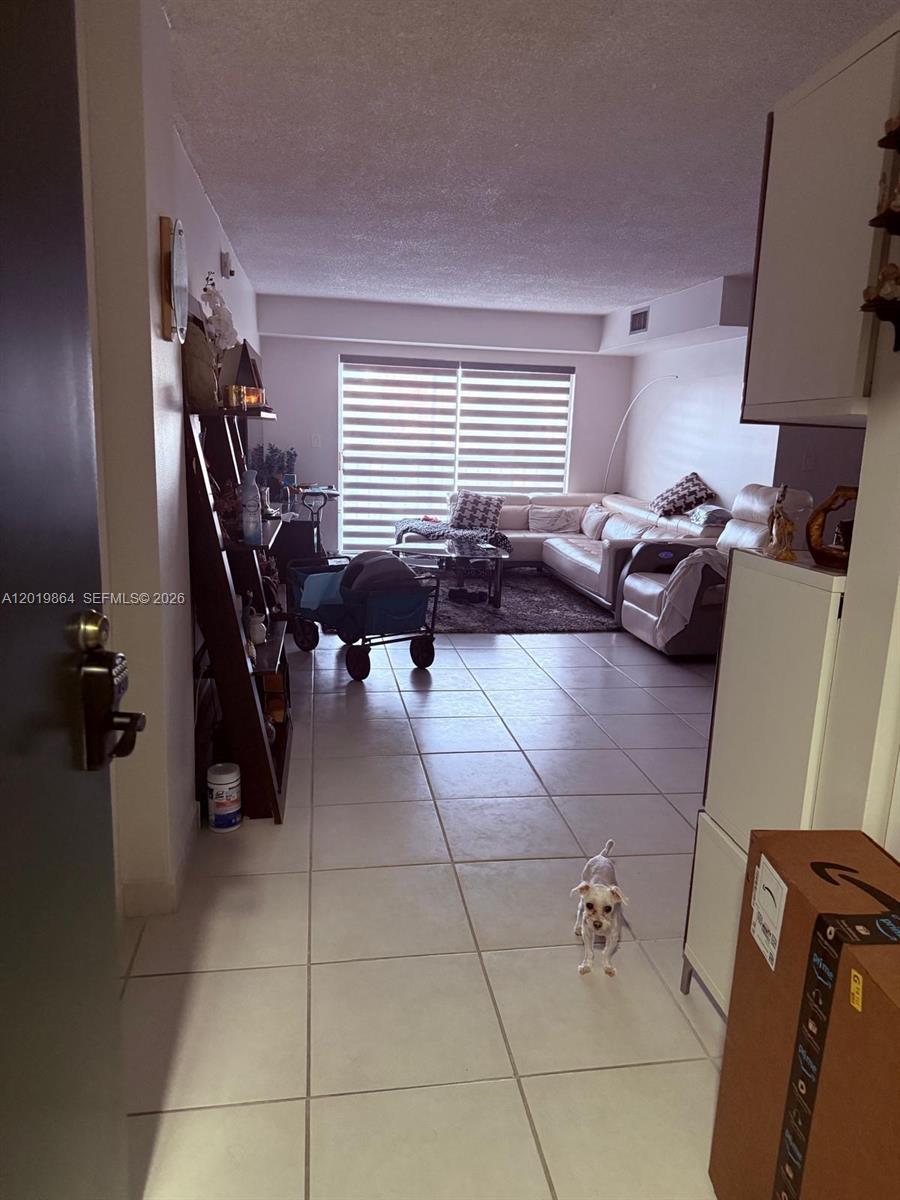 A tiled entryway leads into a living room featuring a large sectional sofa and blinds — 1250 NE 125th St # 317A, North Miami FL 33161, NORTH MIAMI, FL