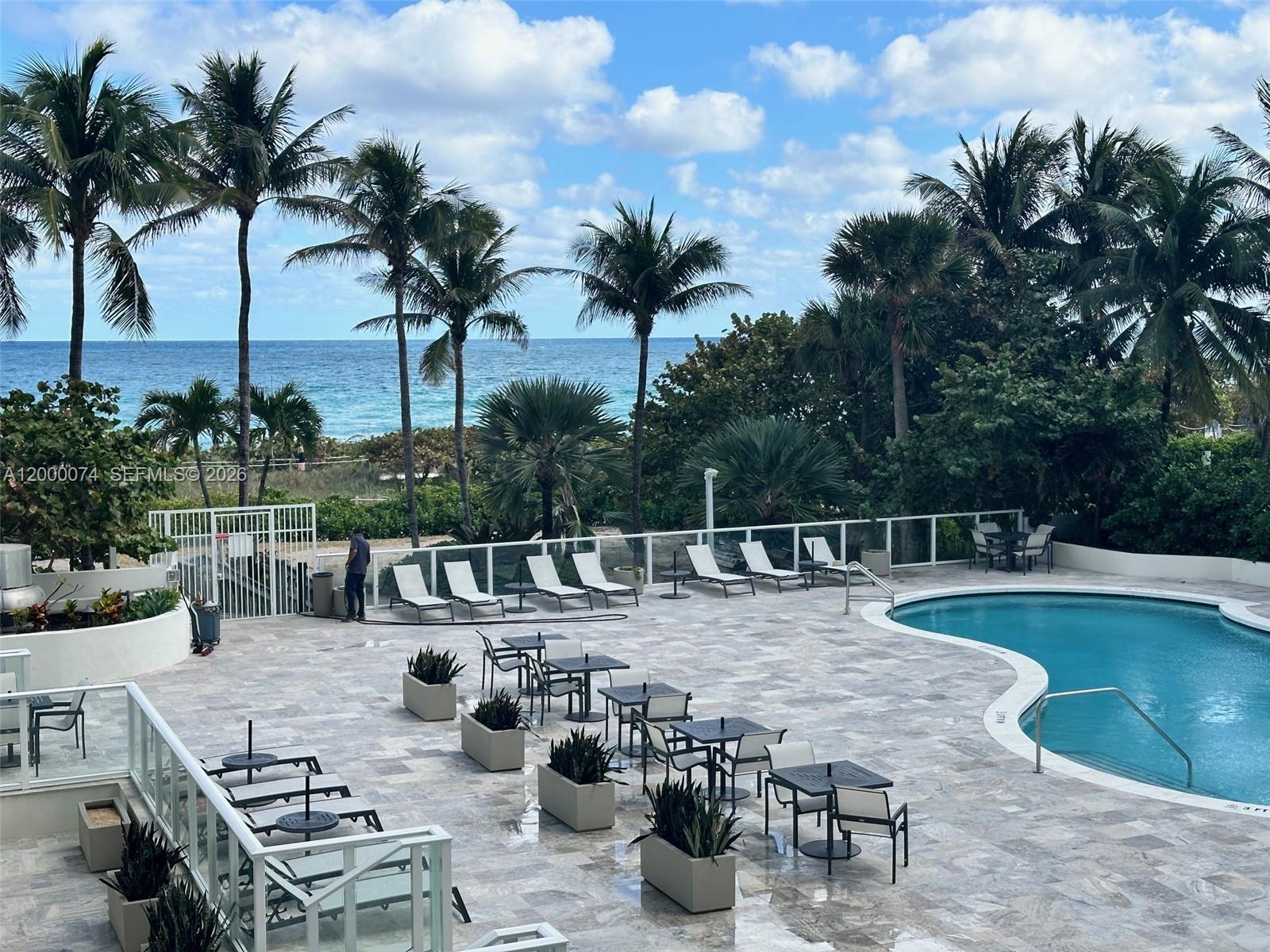 An outdoor pool deck features lounge chairs, dining tables, palm trees, and ocean views — 8925 Collins Ave # 2J, Surfside FL 33154, SURFSIDE, FL