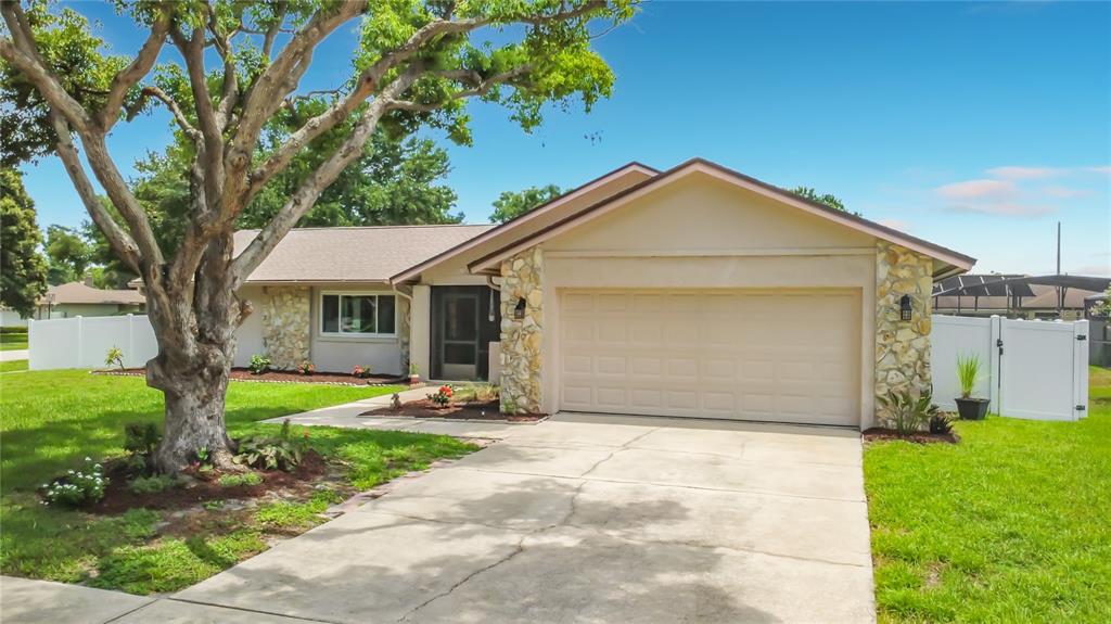 A single-story house with a stone-accented facade, a two-car garage, and a large front tree — 8654 ALEGRE CIRCLE, ORLANDO, FL