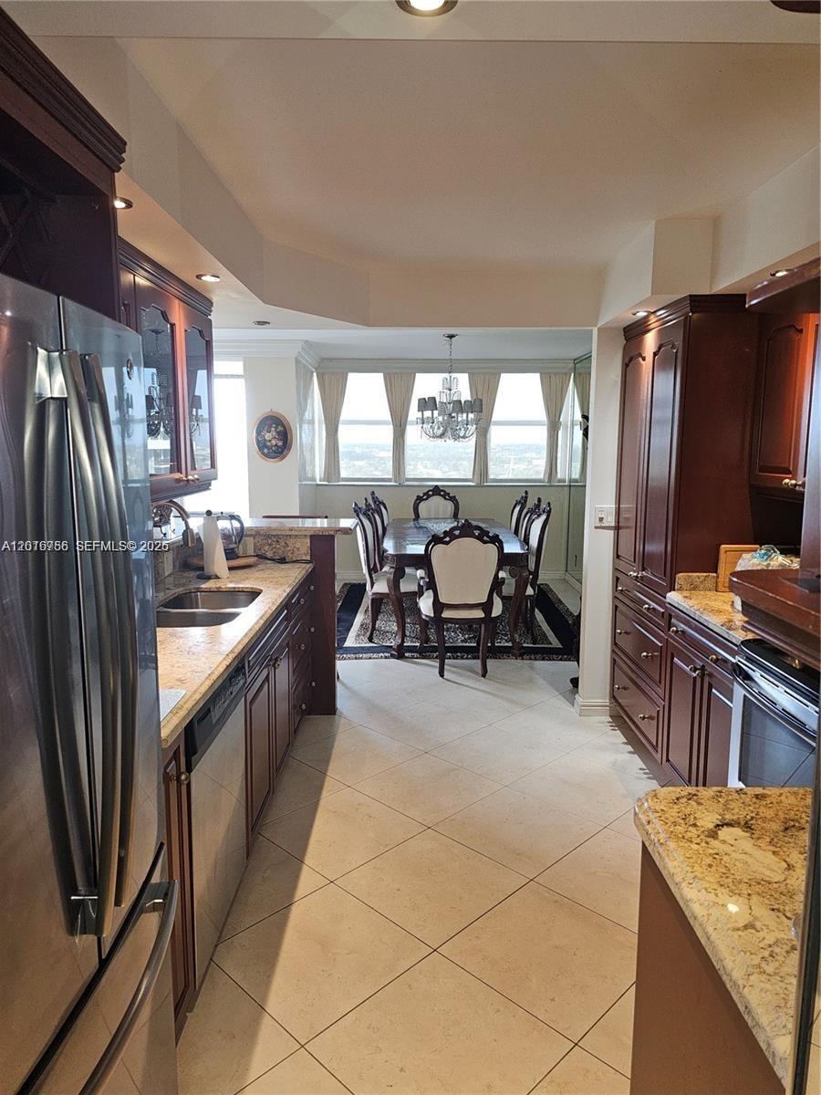 A galley kitchen with dark wood cabinets and granite countertops opens into a dining area — 2049 S Ocean Dr, Hallandale Beach FL 33009, HALLANDALE BEACH, FL