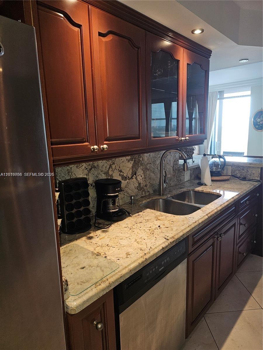 A kitchen features dark wood cabinets, granite countertops, a stainless steel sink, and appliances — 2049 S Ocean Dr, Hallandale Beach FL 33009, HALLANDALE BEACH, FL