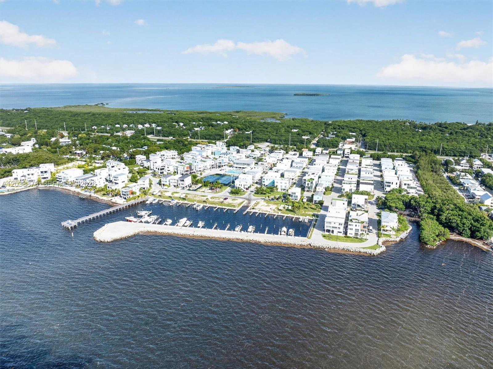 An aerial view shows a coastal residential community with a marina and a long pier — 94825 OVERSEAS HIGHWAY #123, Key Largo FL 33037, KEY LARGO, FL