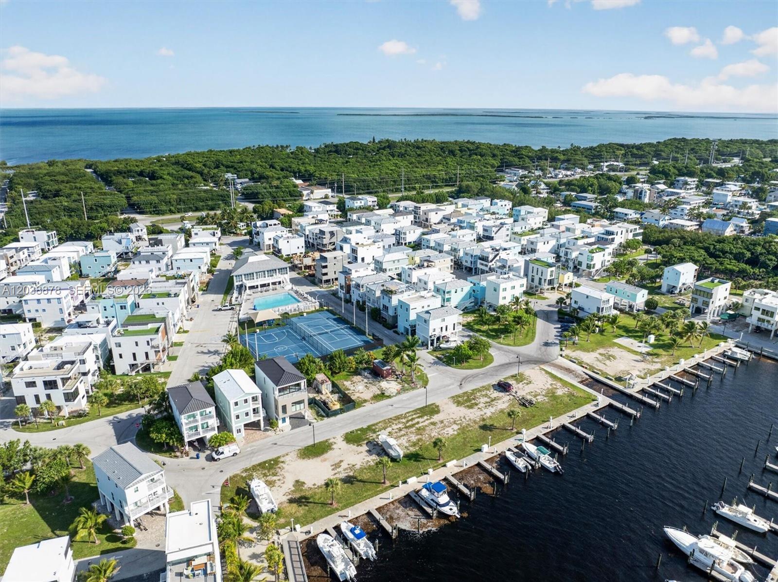 An aerial view shows a coastal residential community with houses, a pool, and boat docks — 94825 OVERSEAS HIGHWAY #123, Key Largo FL 33037, KEY LARGO, FL