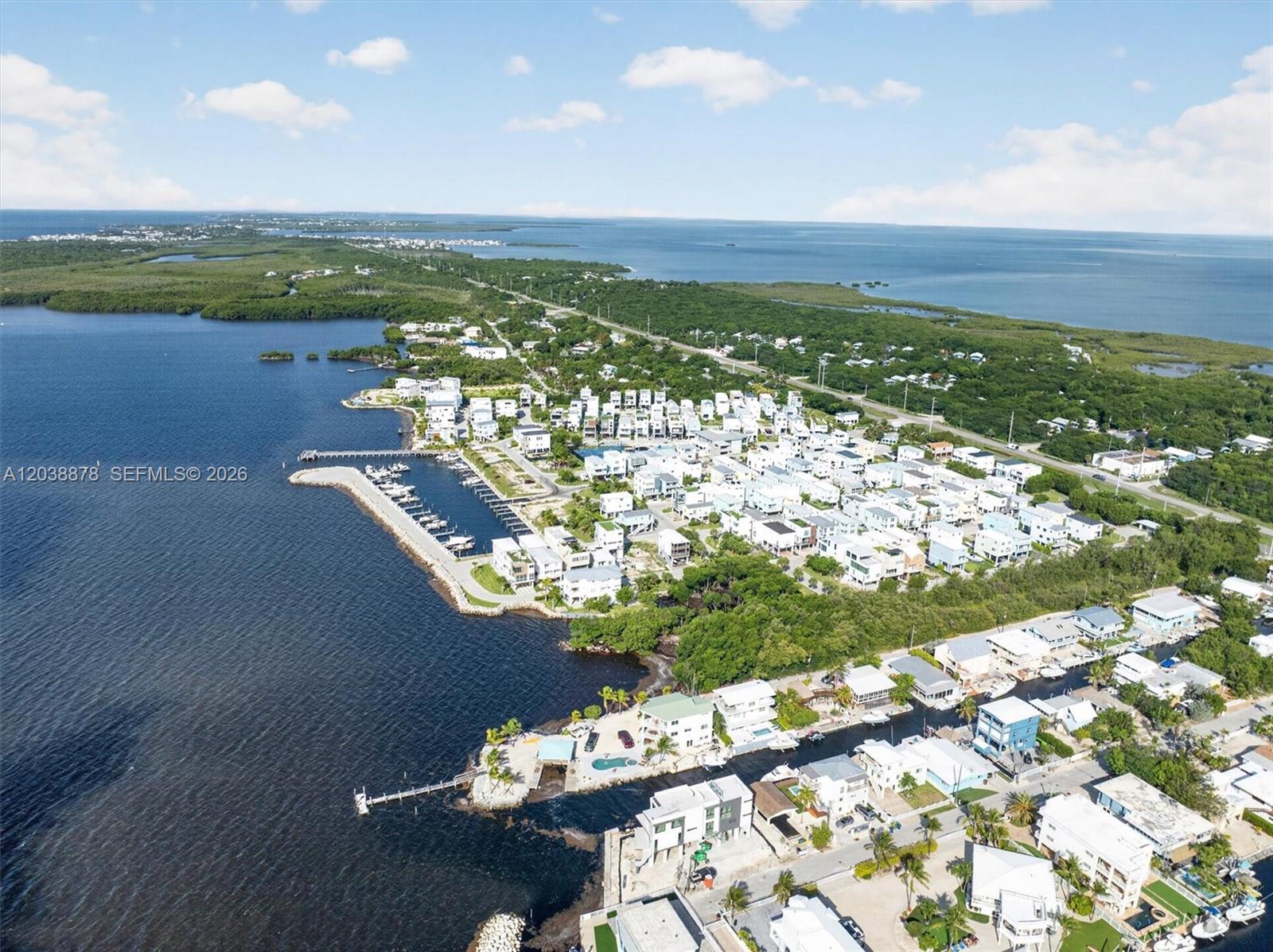 An aerial view shows a coastal residential community with a marina and surrounding water — 94825 OVERSEAS HIGHWAY #123, Key Largo FL 33037, KEY LARGO, FL