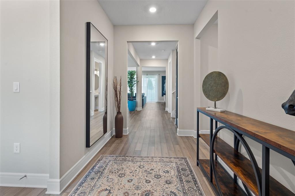 A hallway with wood-look flooring, a large wall mirror, and a console table — 15203 WILLOW RIDGE DRIVE, MONTVERDE, FL