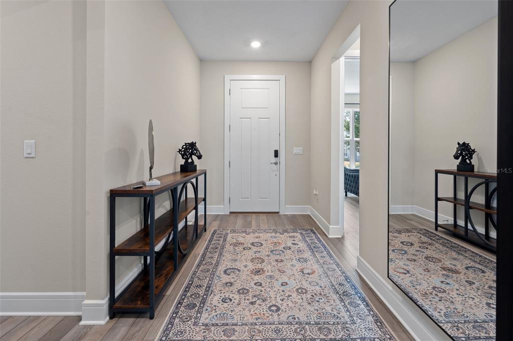 An entryway features a patterned rug, a console table, and a large wall mirror — 15203 WILLOW RIDGE DRIVE, MONTVERDE, FL
