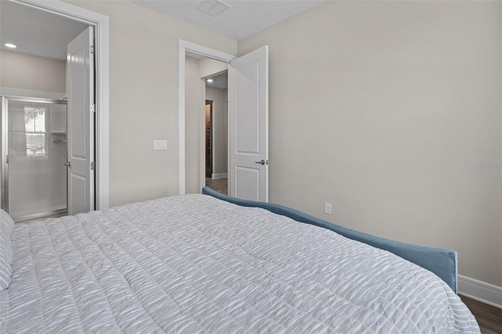 A bedroom features a bed with a blue frame, light walls, and two open doorways — 15203 WILLOW RIDGE DRIVE, MONTVERDE, FL
