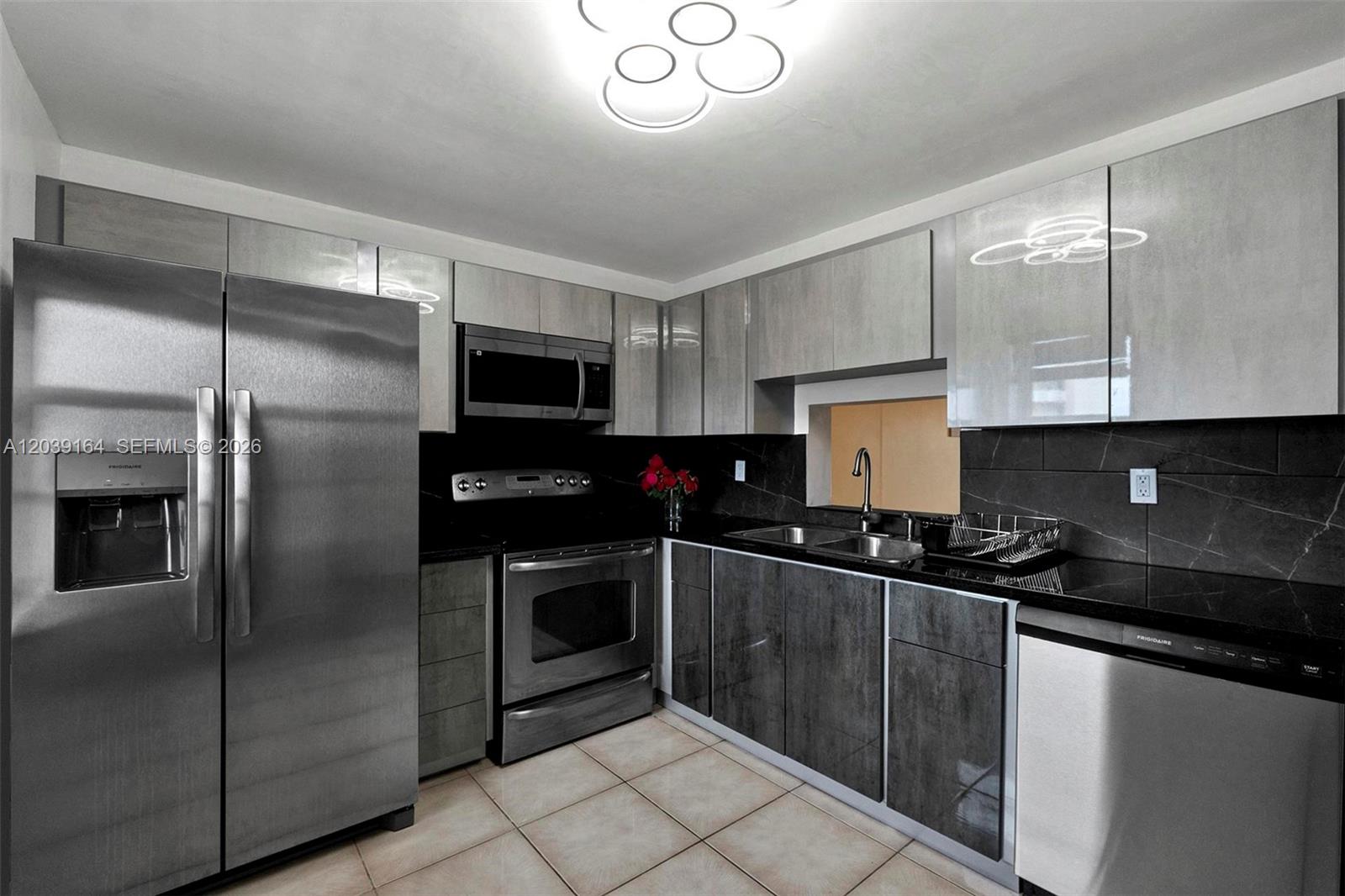 A kitchen features stainless steel appliances, grey cabinetry, and black countertops with a tiled floor — 431 SE 3rd St # 402, Dania Beach FL 33004, DANIA BEACH, FL