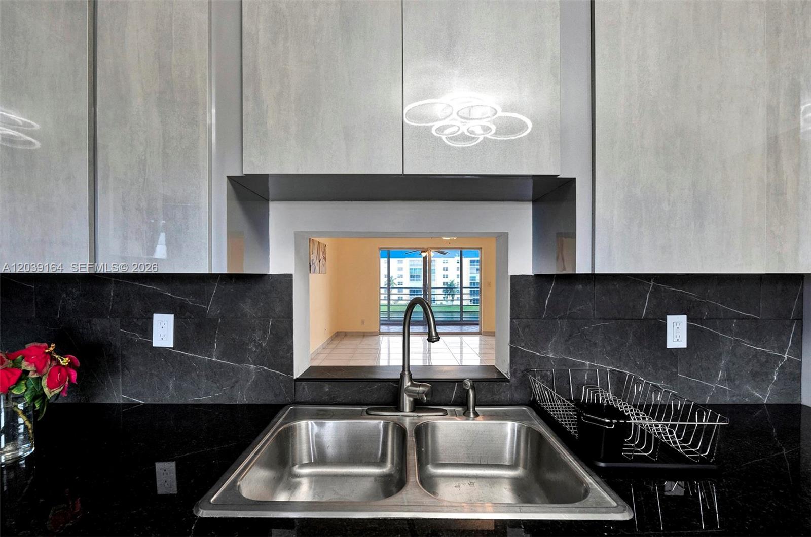 A stainless steel double sink sits in a black countertop against a dark marble backsplash — 431 SE 3rd St # 402, Dania Beach FL 33004, DANIA BEACH, FL