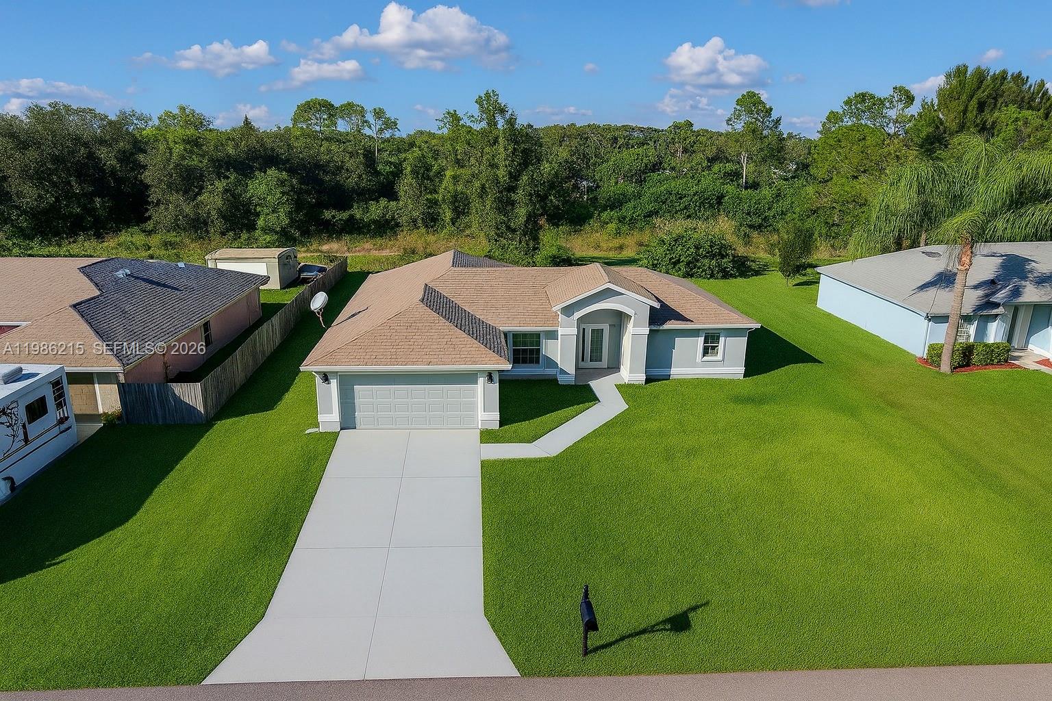 An aerial view of a single-story suburban house with a tan roof and gray exterior — 116 ridgemont Dr, Lehigh Acres FL 33972, LEHIGH ACRES, FL