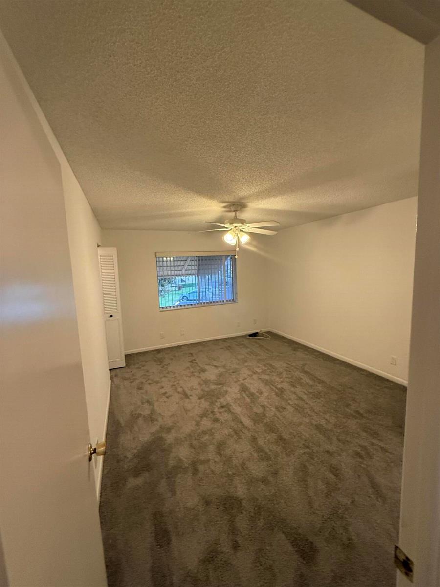 A bedroom with gray carpet, white walls, a ceiling fan, and a single window — 5795 La Pinata Boulevard # 2, FL 33463, FL