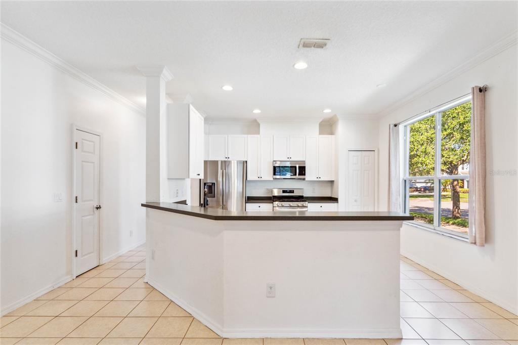 A kitchen with white cabinets, stainless steel appliances, and a breakfast bar on tiled floors — 5007 RIVER GEM AVENUE, WINDERMERE, FL