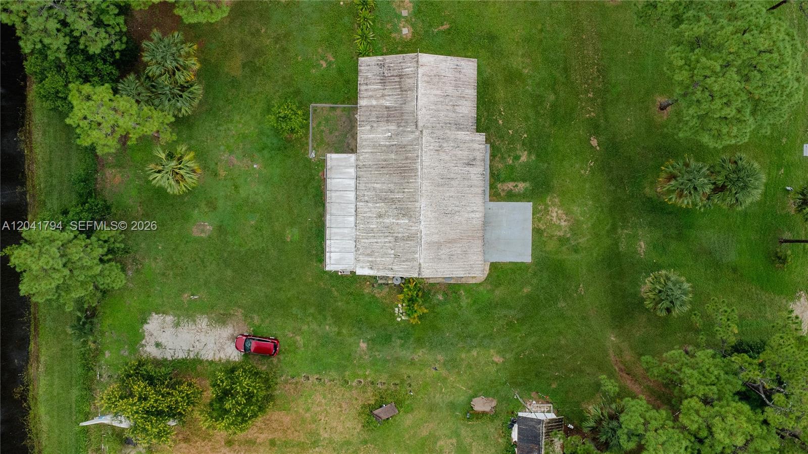 An aerial view shows a house with a weathered roof situated on a large lawn — 9949 N 154th Rd N, Jupiter FL 33478, JUPITER, FL