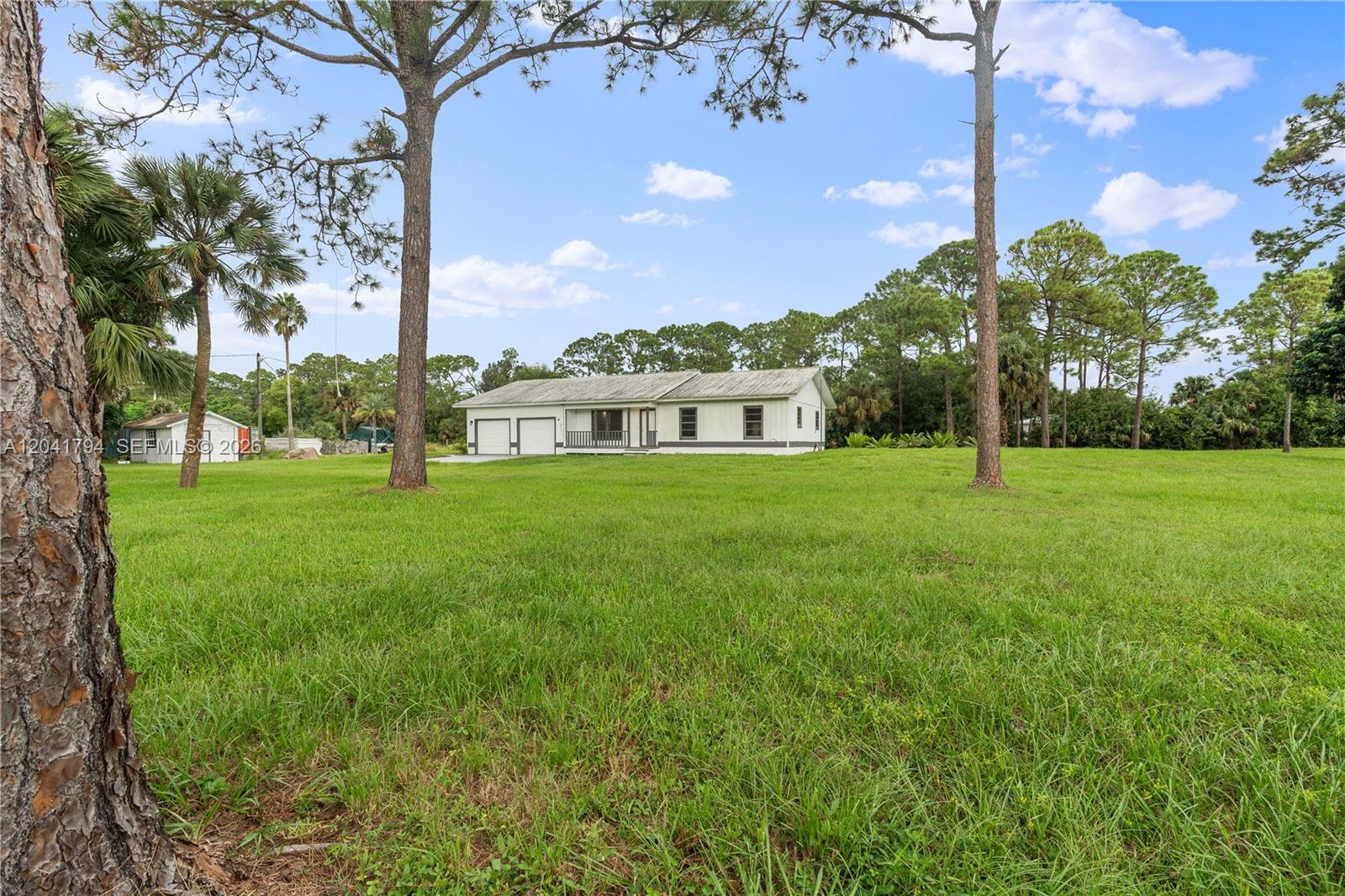 A single-story house with a white exterior sits on a large, grassy lot — 9949 N 154th Rd N, Jupiter FL 33478, JUPITER, FL
