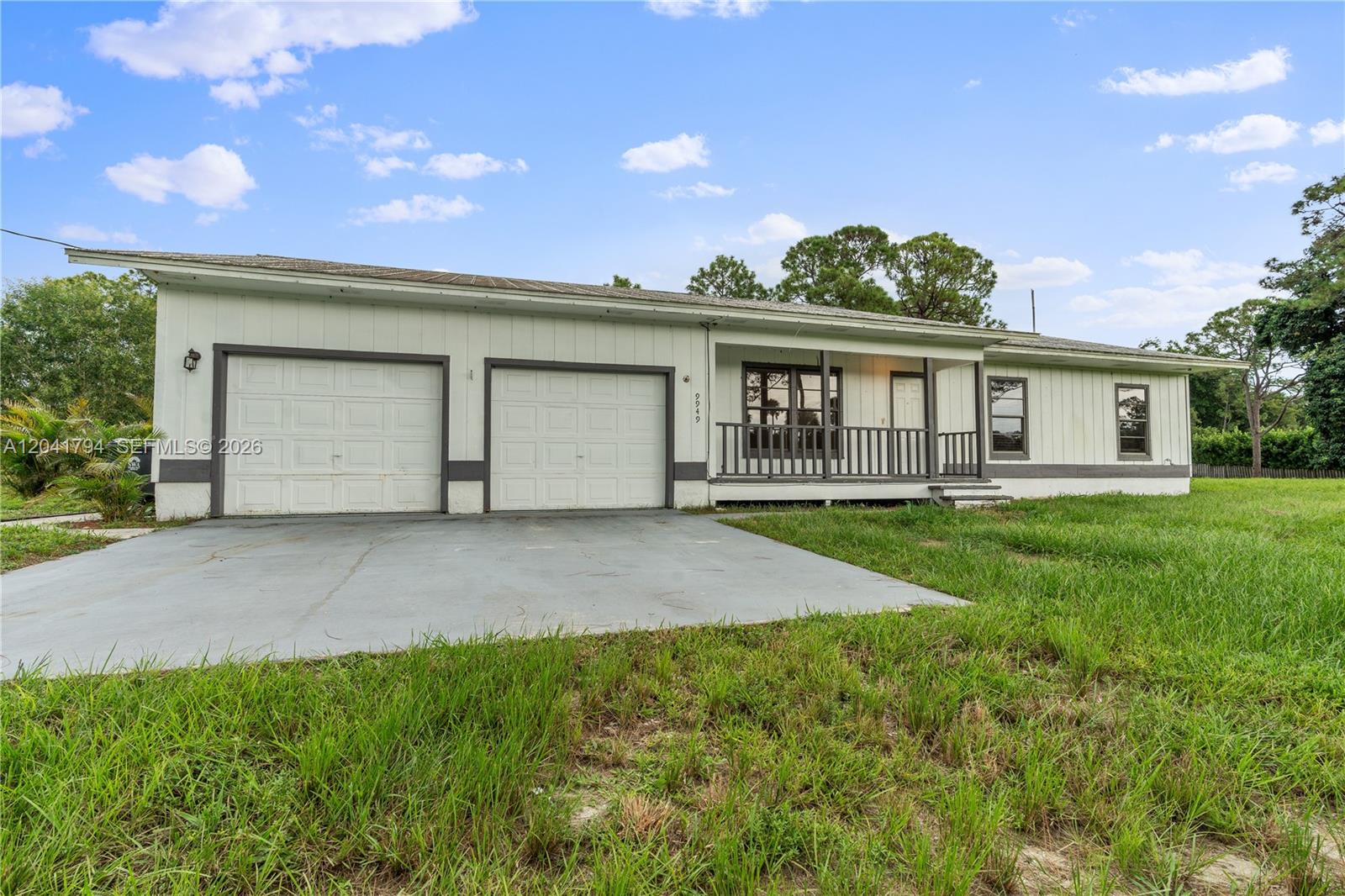 A single-story house with a two-car garage, a front porch, and white vertical siding — 9949 N 154th Rd N, Jupiter FL 33478, JUPITER, FL