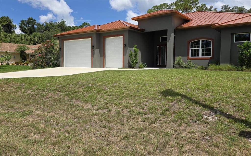A single-story house with a gray exterior, white garage doors, and a copper-colored metal roof — 5223 BALMOR TERRACE, NORTH PORT, FL