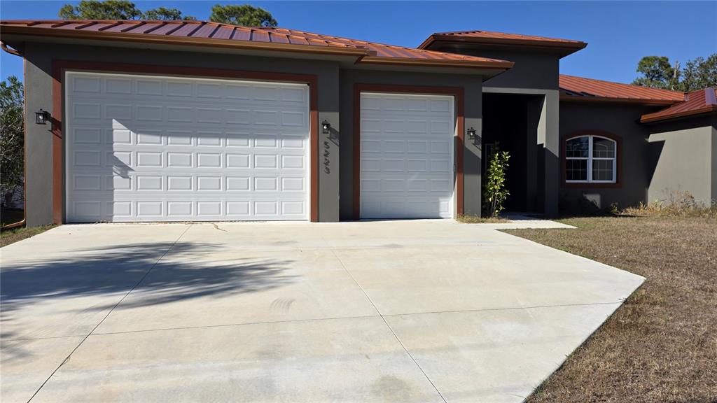 A single-story house with a metal roof, two garage doors, and a concrete driveway — 5223 BALMOR TERRACE, NORTH PORT, FL