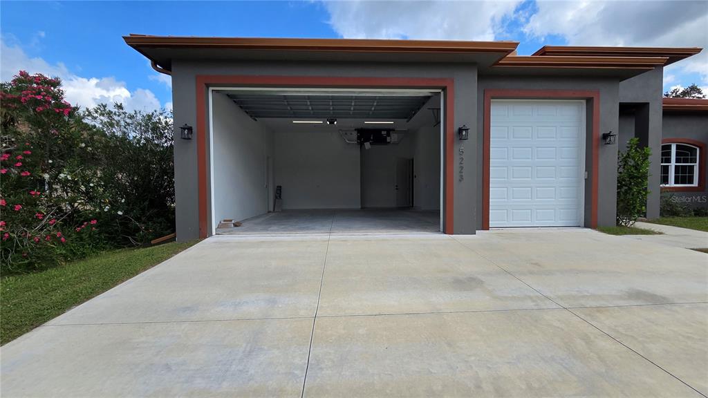 A house exterior features an open garage bay next to a closed white garage door — 5223 BALMOR TERRACE, NORTH PORT, FL