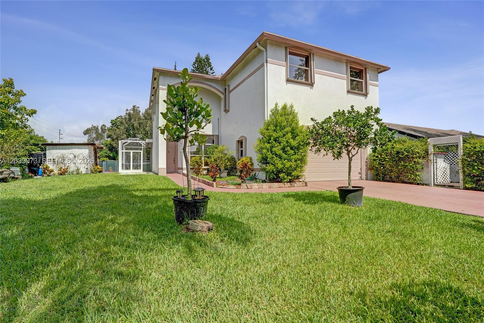 A two-story house with a beige exterior, a front lawn, and a paved driveway — 2151 NW 121st Ave, Plantation FL 33323, PLANTATION, FL