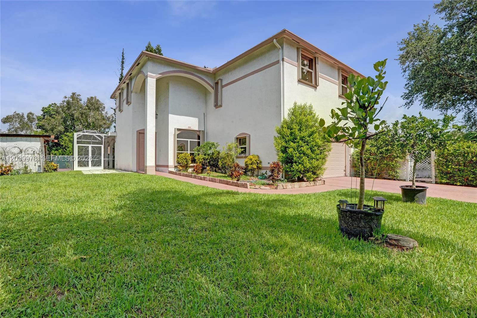A two-story stucco house with a side-entry garage and a front lawn — 2151 NW 121st Ave, Plantation FL 33323, PLANTATION, FL