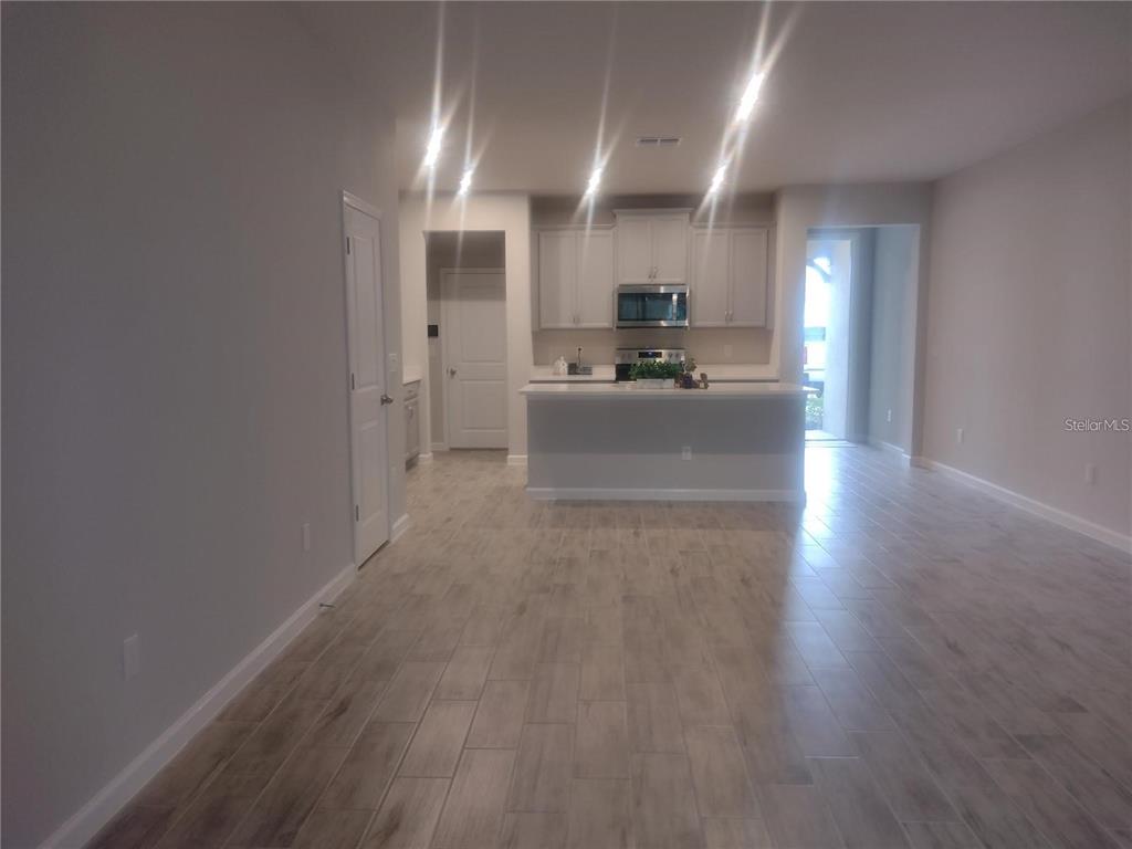 A kitchen with light-colored cabinets and an island overlooks an open-concept living area — 26010 WOVEN WICKER BEND, LUTZ, FL