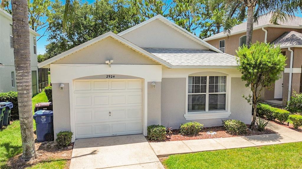 A single-story house with a white garage door, light gray stucco walls, and a shingled roof — 2924 KOKOMO LOOP, HAINES CITY, FL