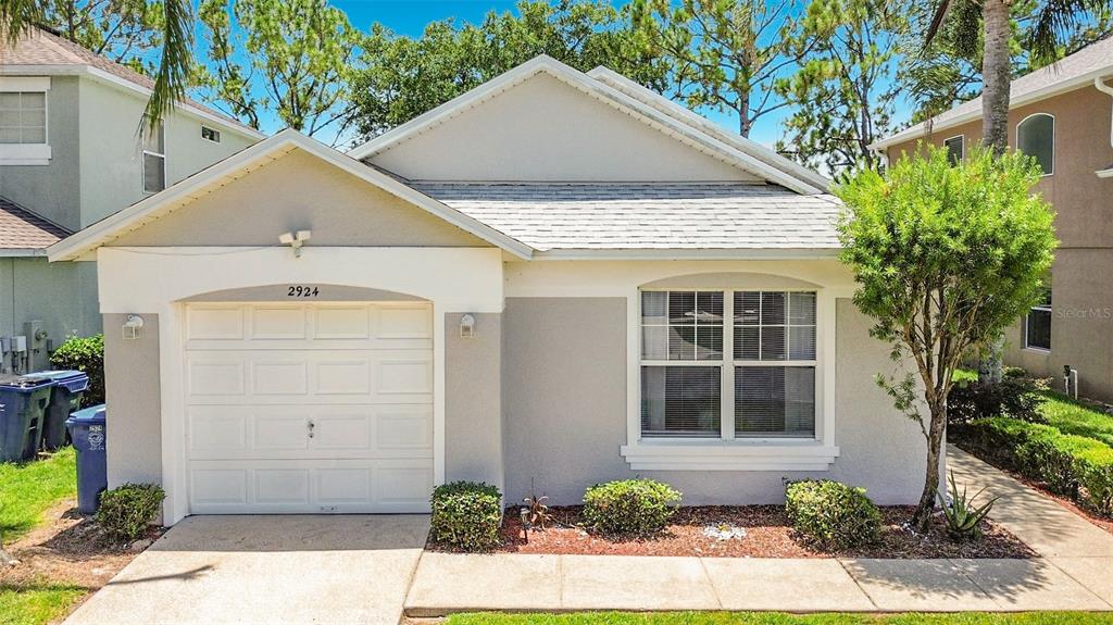 A single-story house with a white garage door, gray stucco exterior, and a front window — 2924 KOKOMO LOOP, HAINES CITY, FL