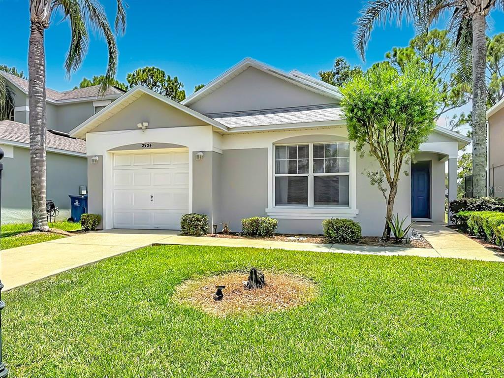 A single-story house with a white garage, gray exterior, and a front lawn — 2924 KOKOMO LOOP, HAINES CITY, FL