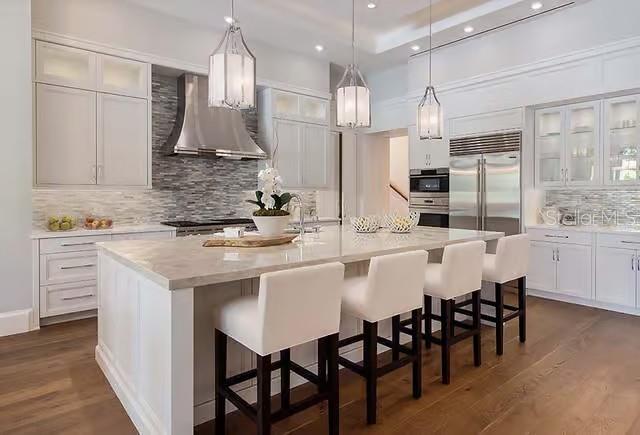 A modern kitchen features white cabinetry, a large stone-topped island with bar stools, and stainless appliances — 29901 OSPREY COURT, TAVARES, FL