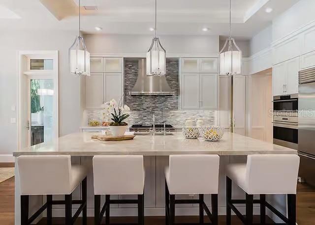 A modern kitchen features a large island with four white bar stools and pendant lighting — 29901 OSPREY COURT, TAVARES, FL