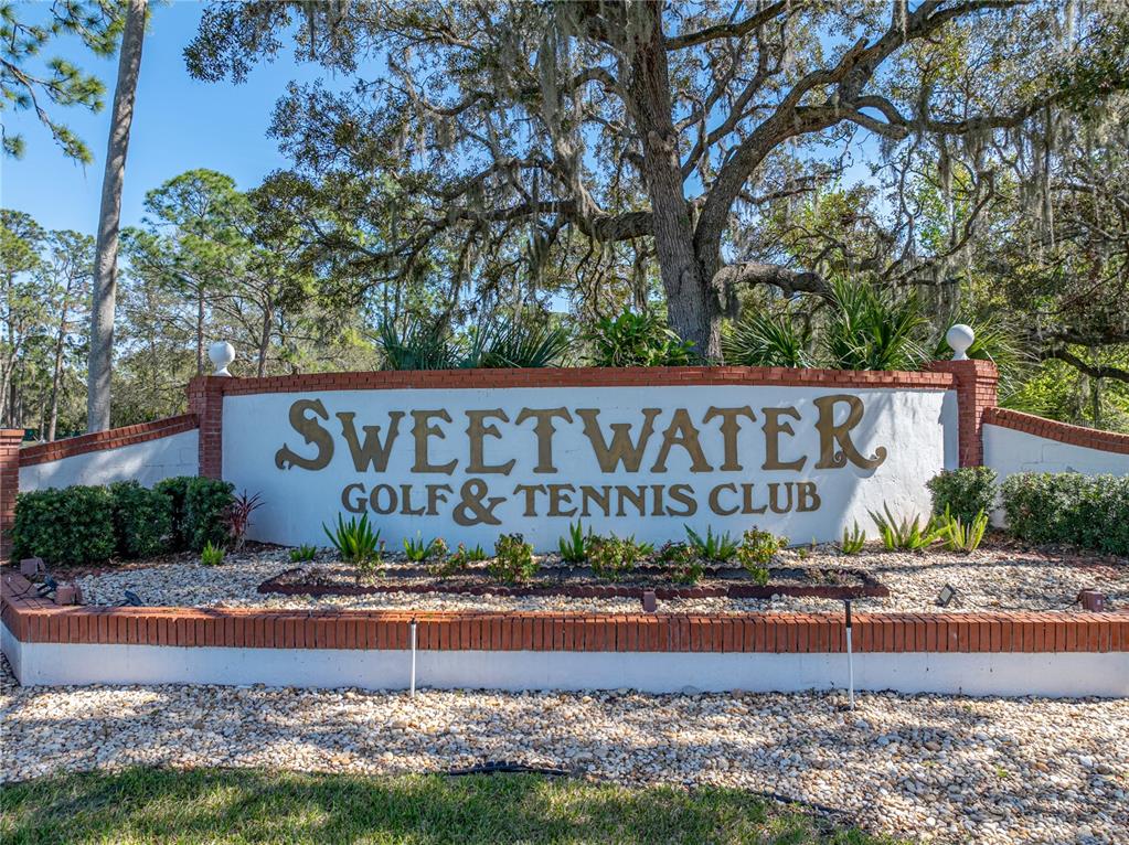 A brick and stucco monument sign displays the name Sweetwater Golf & Tennis Club — 33 EDINBURGH DRIVE, HAINES CITY, FL