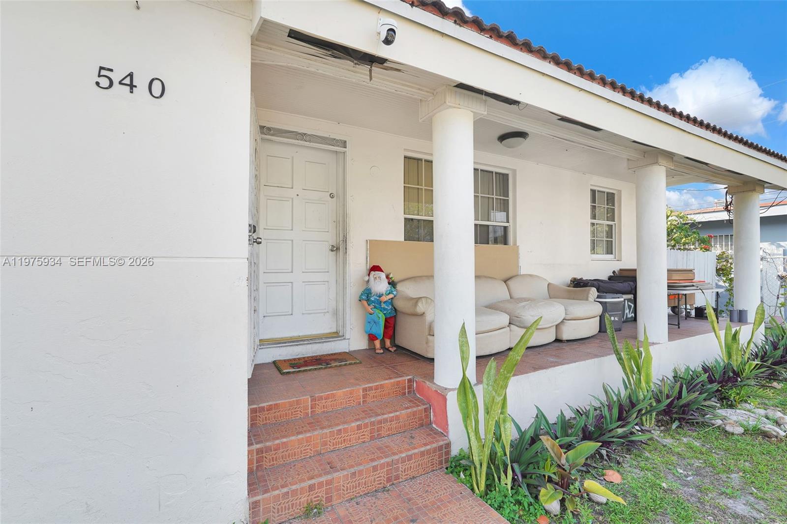 A white house exterior features a covered porch with columns, a sofa, and stairs — 538 NW 20th Ave, Miami FL 33125, MIAMI, FL
