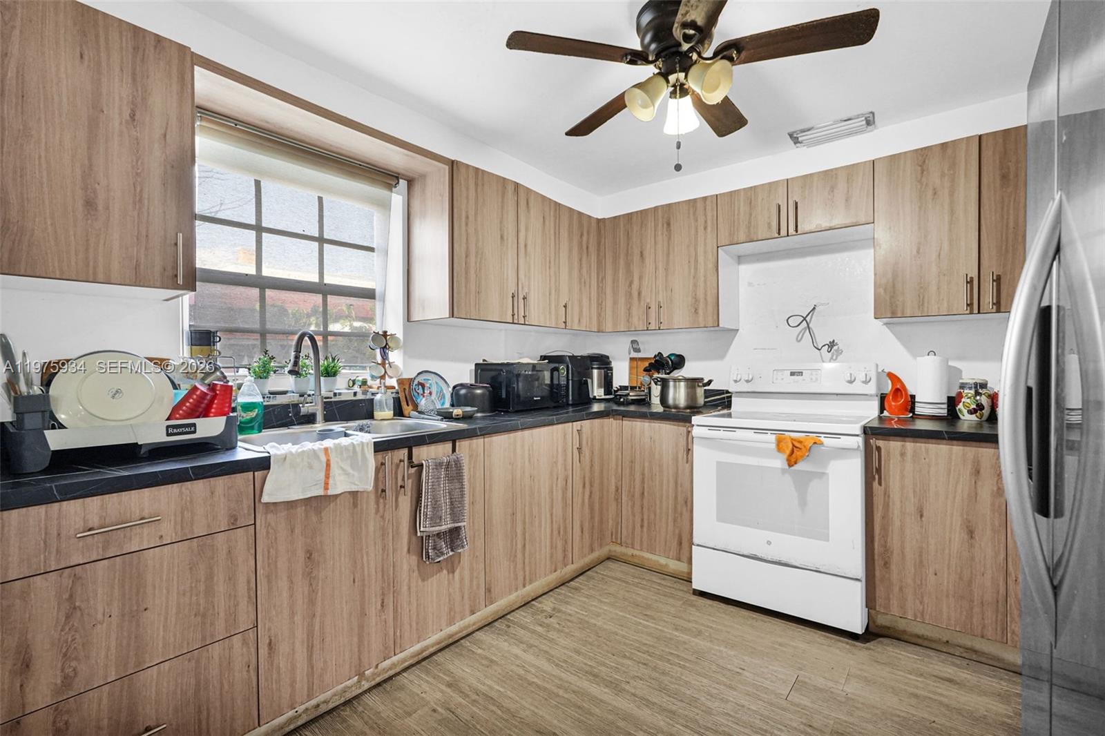 A kitchen features wood-grain cabinets, dark countertops, a white stove, and a ceiling fan — 538 NW 20th Ave, Miami FL 33125, MIAMI, FL
