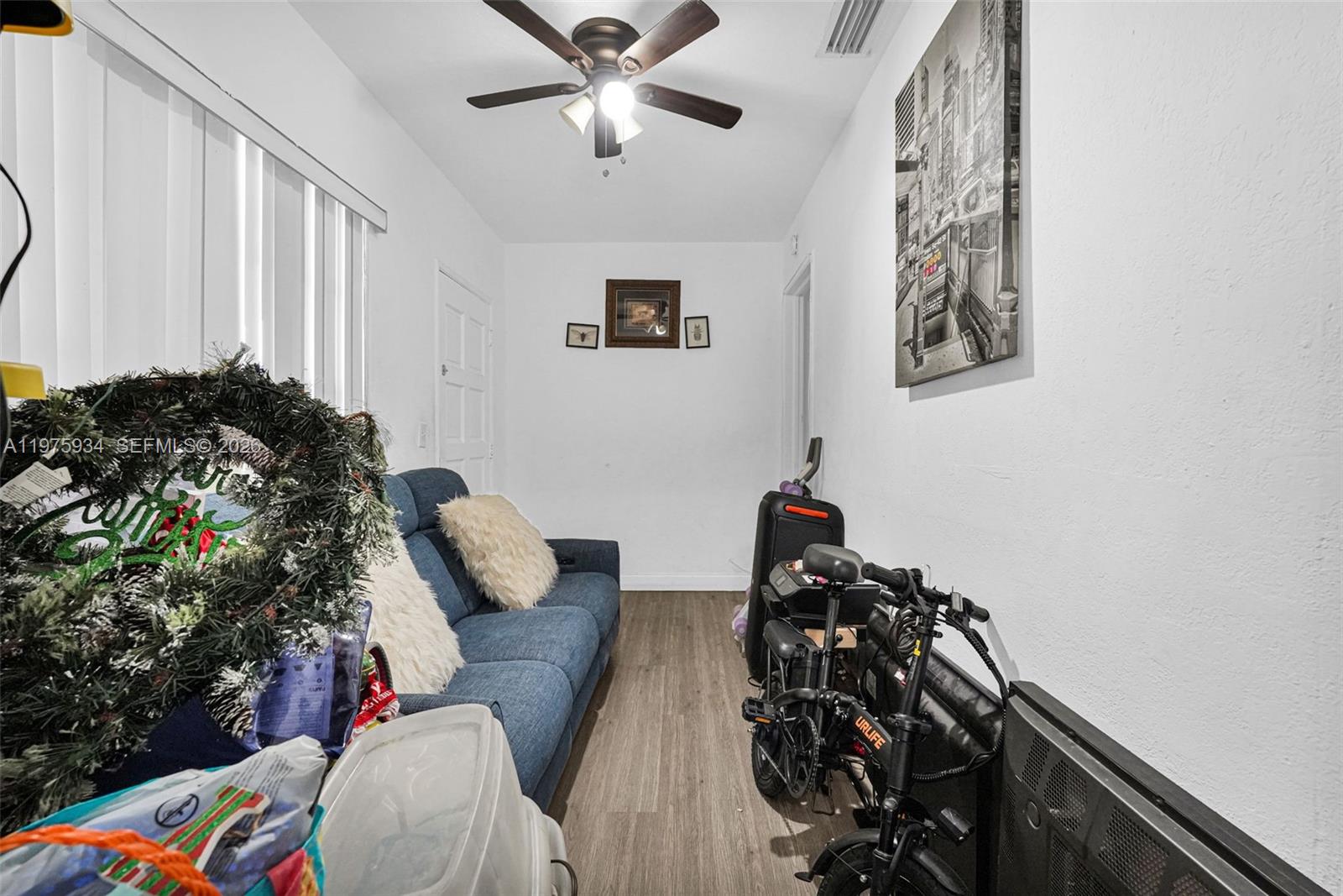 A narrow room features a blue sofa, a folding bicycle, and a ceiling fan — 538 NW 20th Ave, Miami FL 33125, MIAMI, FL