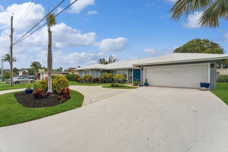 A gray single-story house features a large concrete driveway, a two-car garage, and landscaping — 13 Little Harbor Way, Deerfield Beach FL 33441, DEERFIELD BEACH, FL