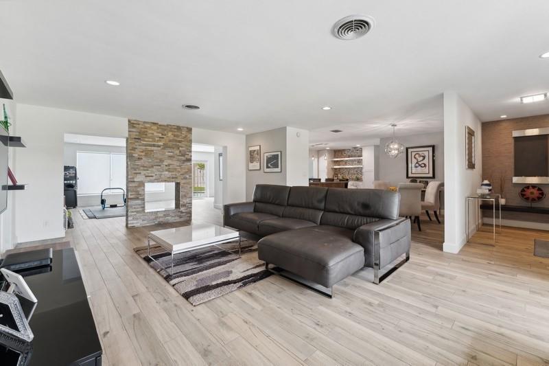 A living room features a stone fireplace, a grey sectional sofa, and light wood flooring — 13 Little Harbor Way, Deerfield Beach FL 33441, DEERFIELD BEACH, FL