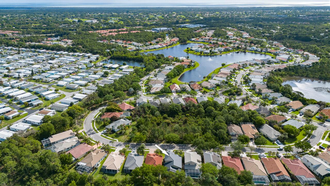 An aerial view shows a residential neighborhood with houses, a lake, and dense green trees — 7213 SE Magellan Lane, Stuart FL 34997, STUART, FL