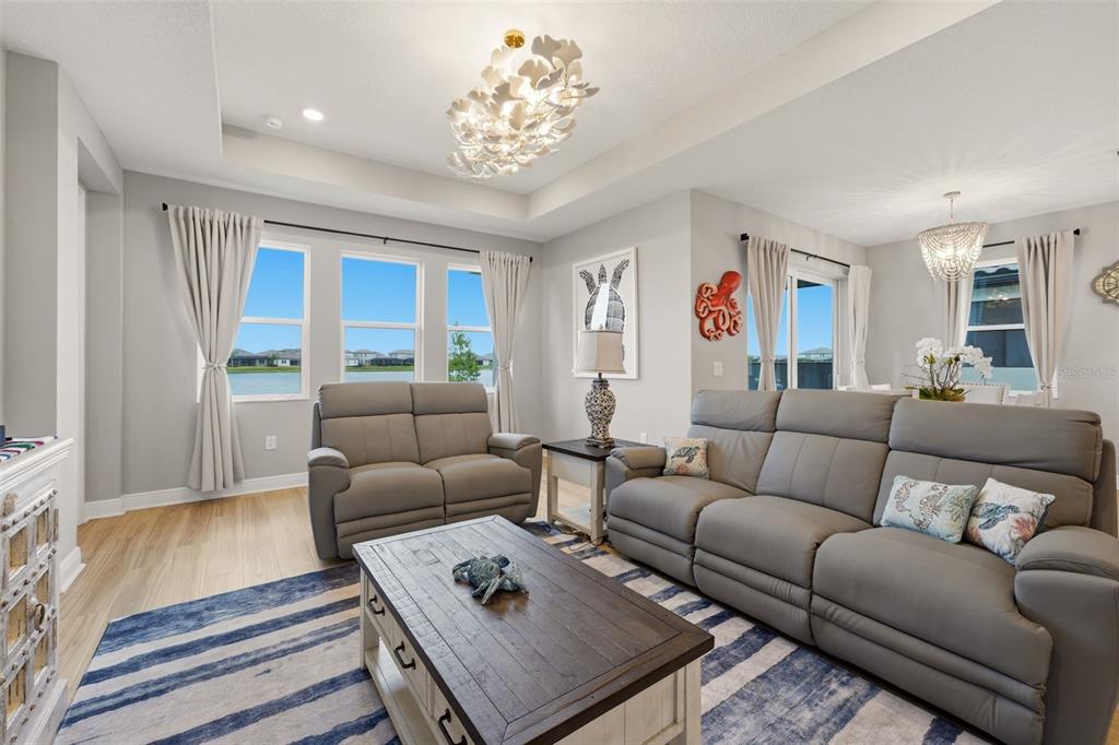 A living room features gray leather furniture, a striped rug, and a lake view — 17325 SAVORY MIST CIRCLE, BRADENTON, FL