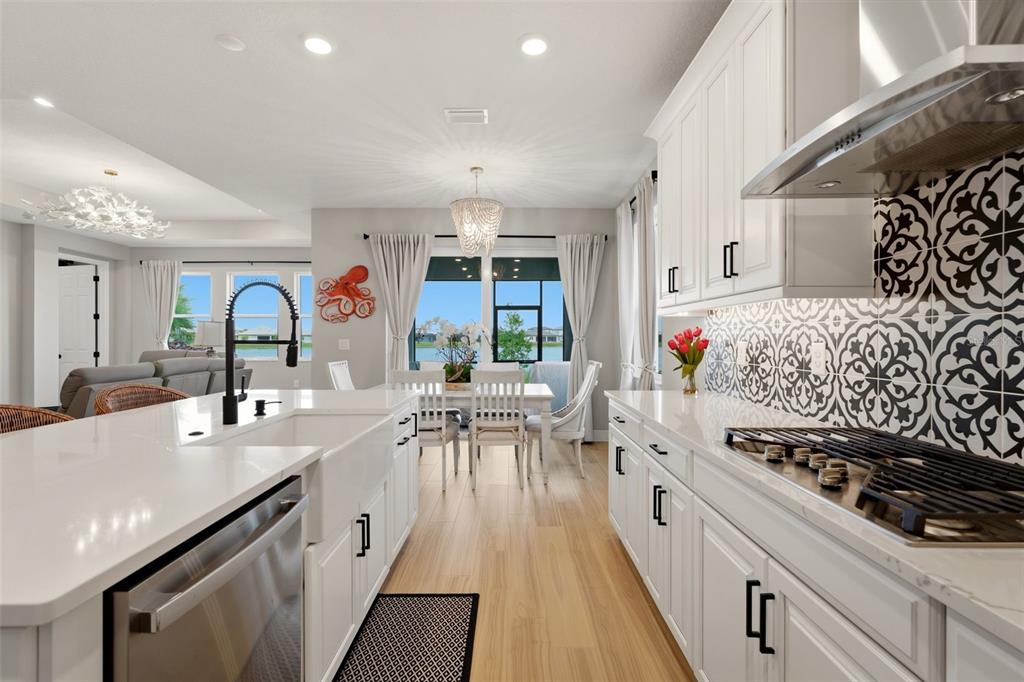 A modern kitchen features white cabinets, quartz countertops, and a patterned tile backsplash — 17325 SAVORY MIST CIRCLE, BRADENTON, FL