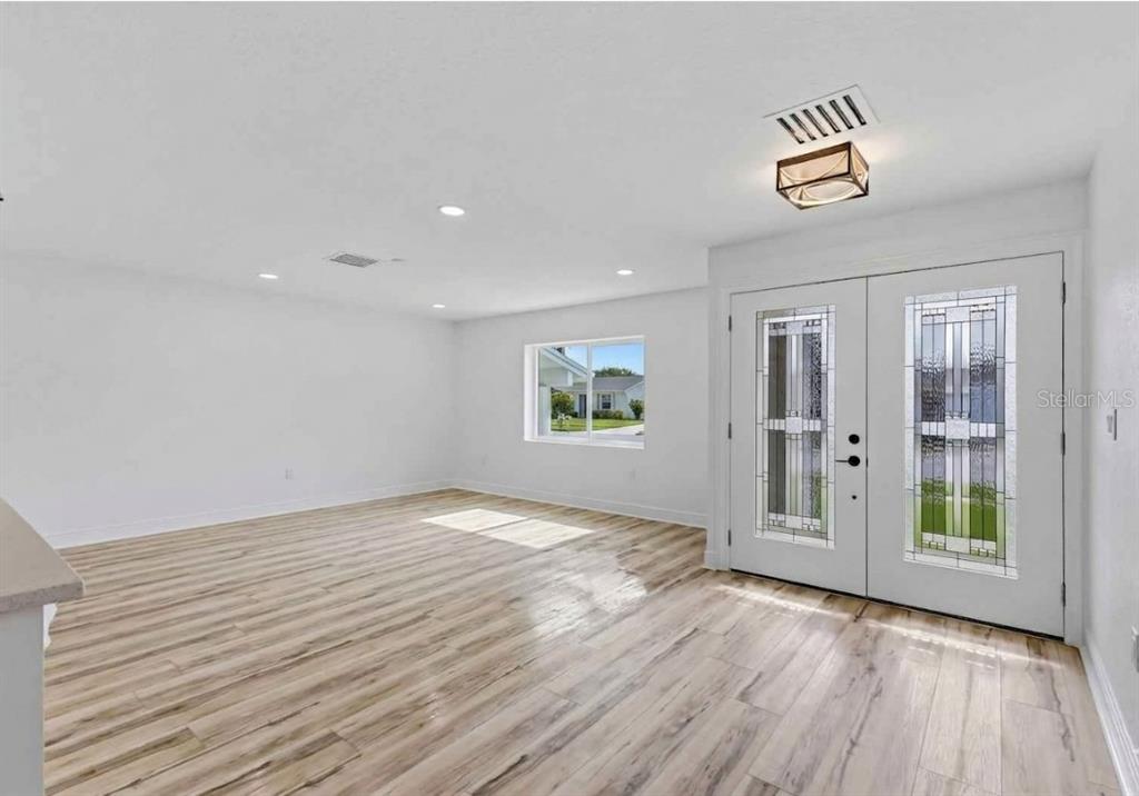 A bright room with light wood-look flooring, white walls, and double glass-paneled entry doors — 9354 119TH WAY, SEMINOLE, FL