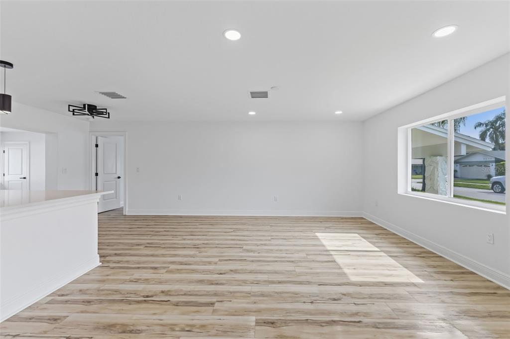 An empty room with light wood-look flooring, white walls, recessed lighting, and a large window — 9354 119TH WAY, SEMINOLE, FL
