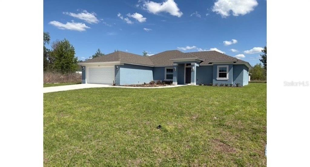 A single-story blue house with a two-car garage and a front porch under a roof — 12833 SW 72ND TERRACE ROAD, OCALA, FL