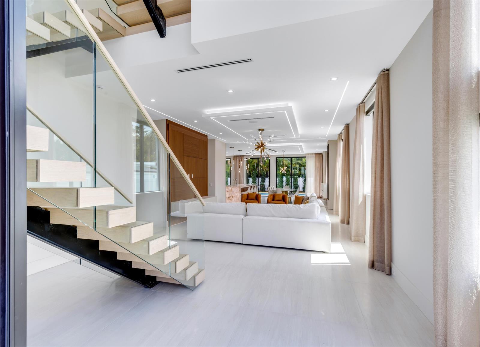 A modern living room features a floating staircase, white sofa, and recessed ceiling lighting — 310 NE 2nd Street, Boca Raton FL 33432, BOCA RATON, FL