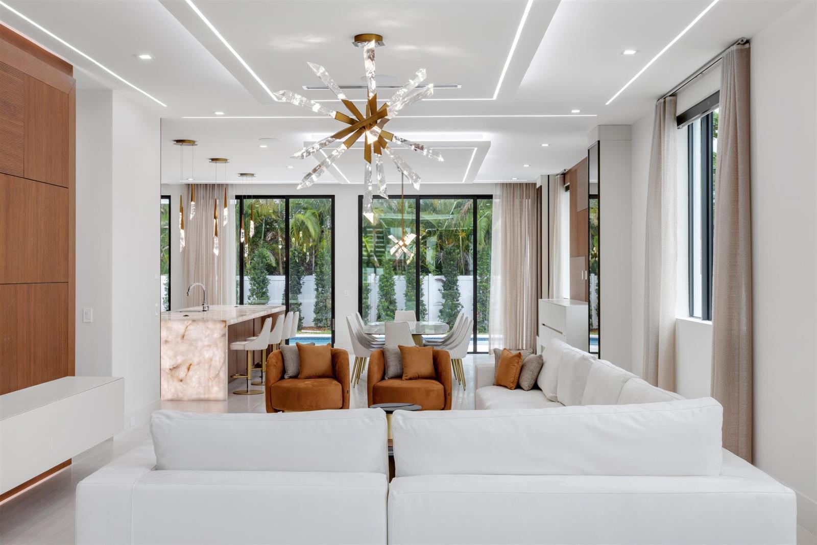 A modern open-concept living and dining area features white sofas, amber armchairs, and marble accents — 310 NE 2nd Street, Boca Raton FL 33432, BOCA RATON, FL